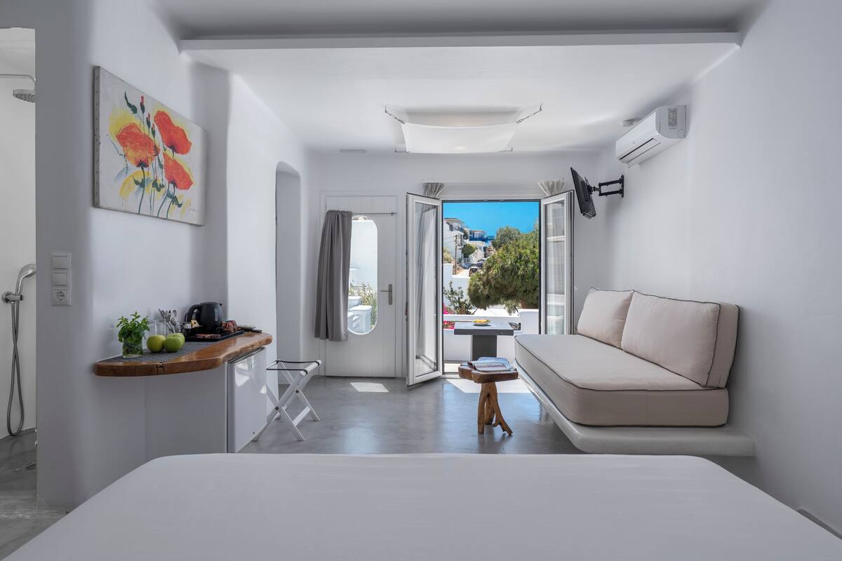 A modern, minimalist room with a sofa, a dining table, and a view of the outdoors.