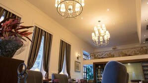 A hotel lobby with a chandelier, seating area, and a staircase. - Kotoni (Tirana)