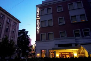 A hotel with a prominent sign, multiple windows, and a well-lit entrance. - Kotoni (Tirana)