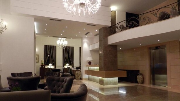 A spacious lobby with a chandelier, a reception desk, and a modern elevator. - Kotoni (Tirana)