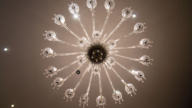A chandelier with multiple arms and crystal-like decorations. - Kotoni (Tirana)