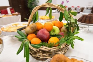 A wicker basket filled with fruits and greenery on a table. - Kotoni (Tirana)