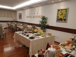 Un comedor de hotel con una mesa de buffet, sillas y una pared con el nombre del hotel.