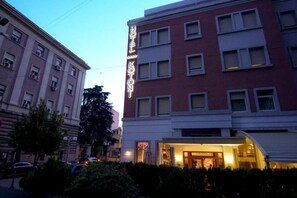 Un edificio de hotel con un letrero llamativo, varias ventanas y una entrada bien iluminada.