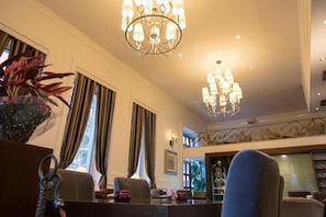 Een hotel lobby met een kroonluchter, een zithoek en een trap.