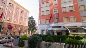 A hotel with a red facade, multiple windows, and a flag. - Kotoni (Tirana)