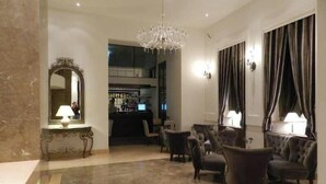 A lobby with a chandelier, a bar area, and seating. - Kotoni (Tirana)