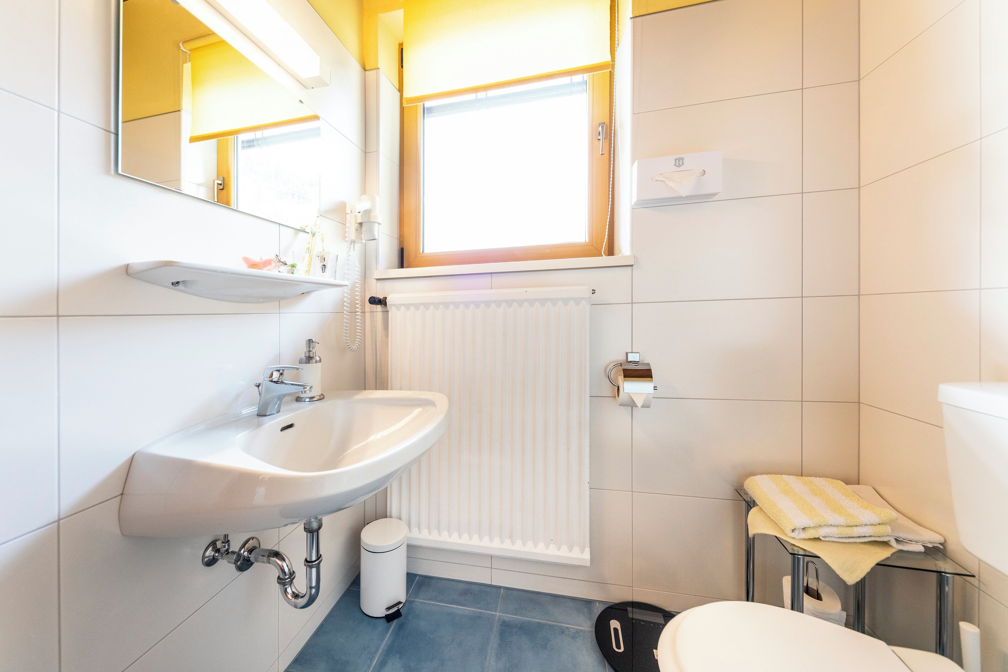 Un bagno moderno con lavandino, specchio e water bianchi.