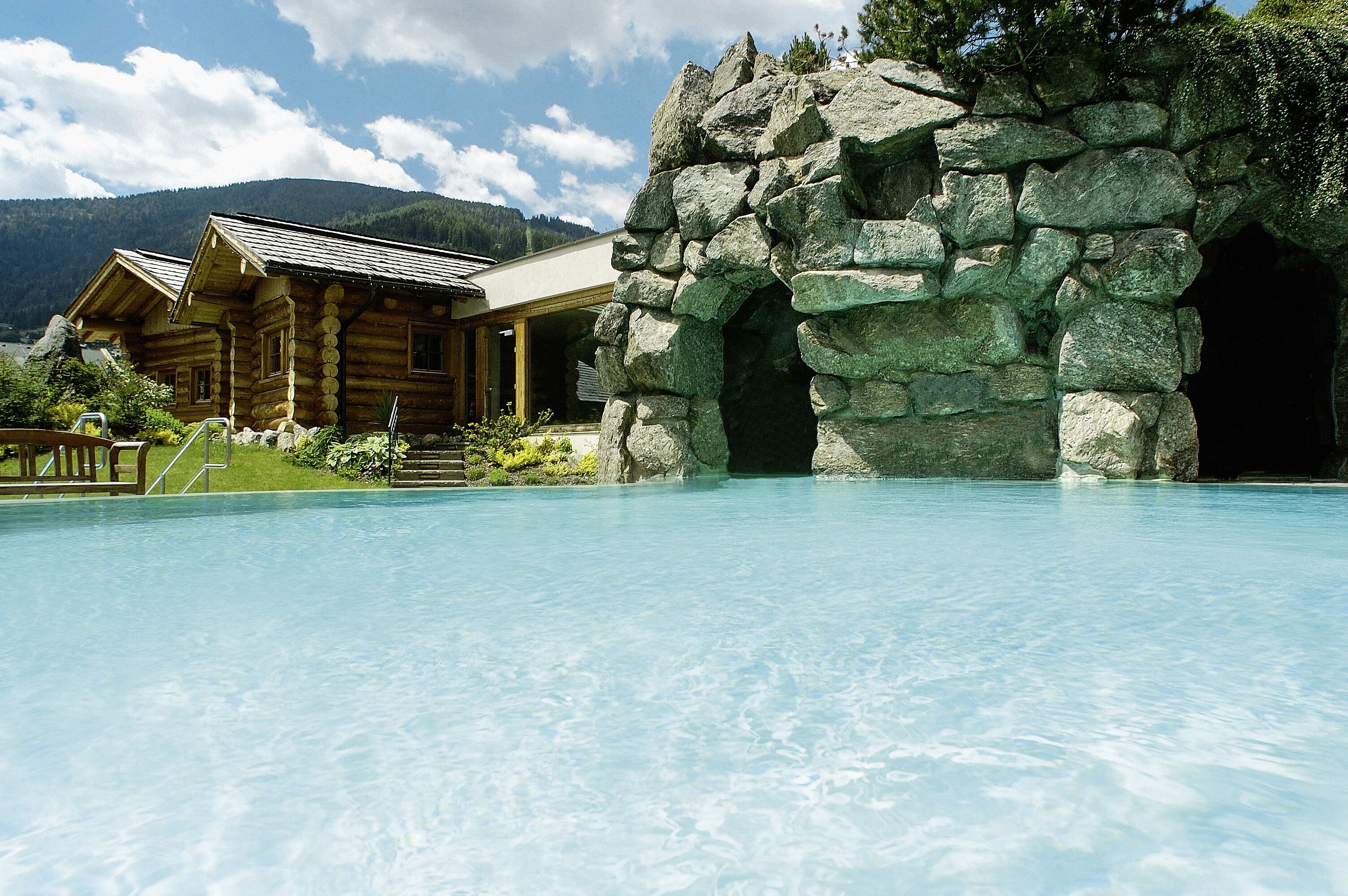 A wooden lodge with a pool and a stone archway.