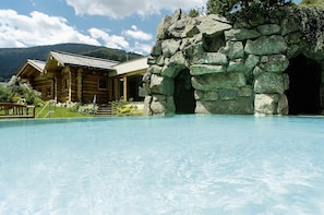 A wooden lodge with a pool and a stone archway.
