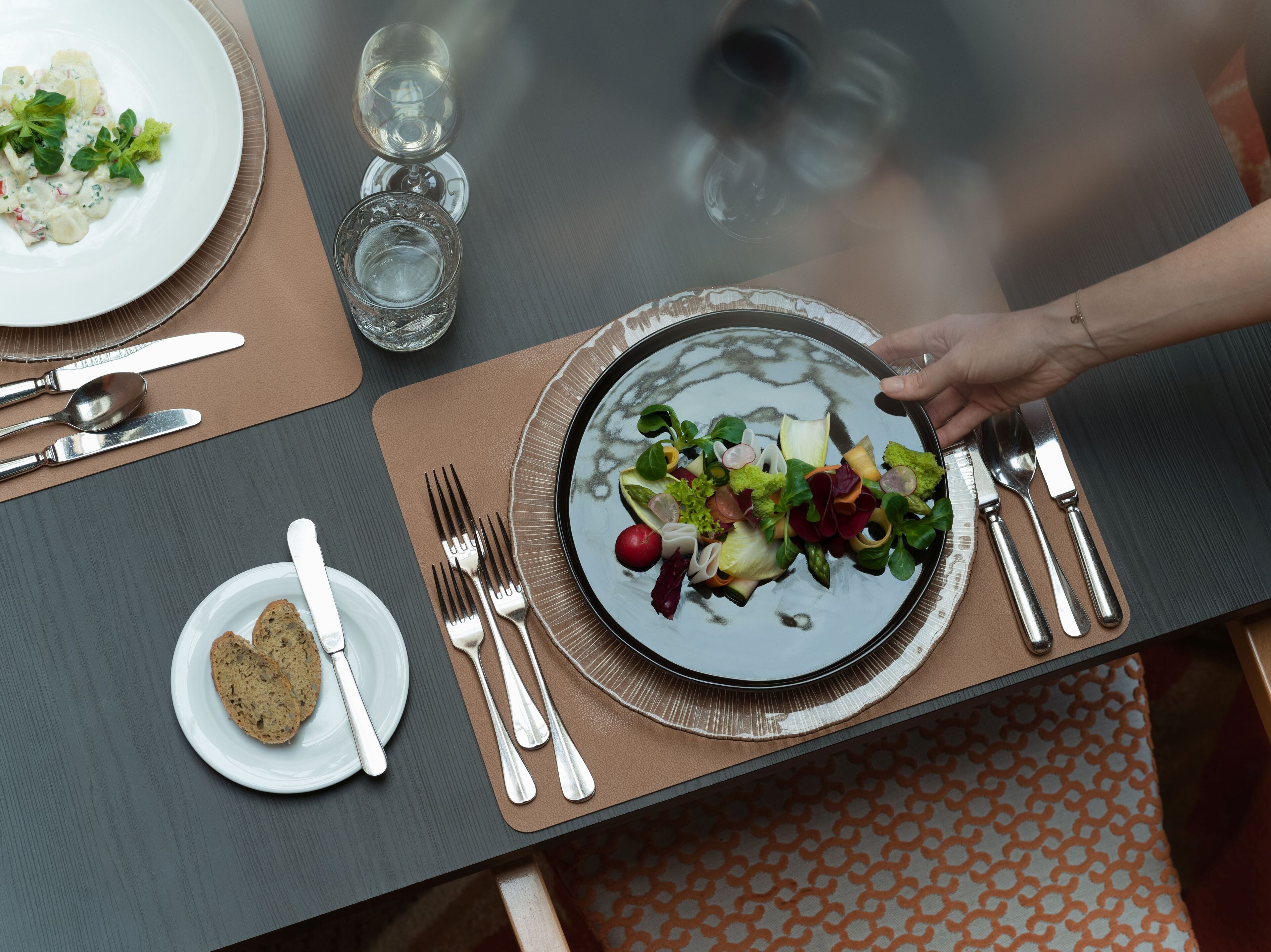 A dining table with a plate of food, cutlery, and glasses.