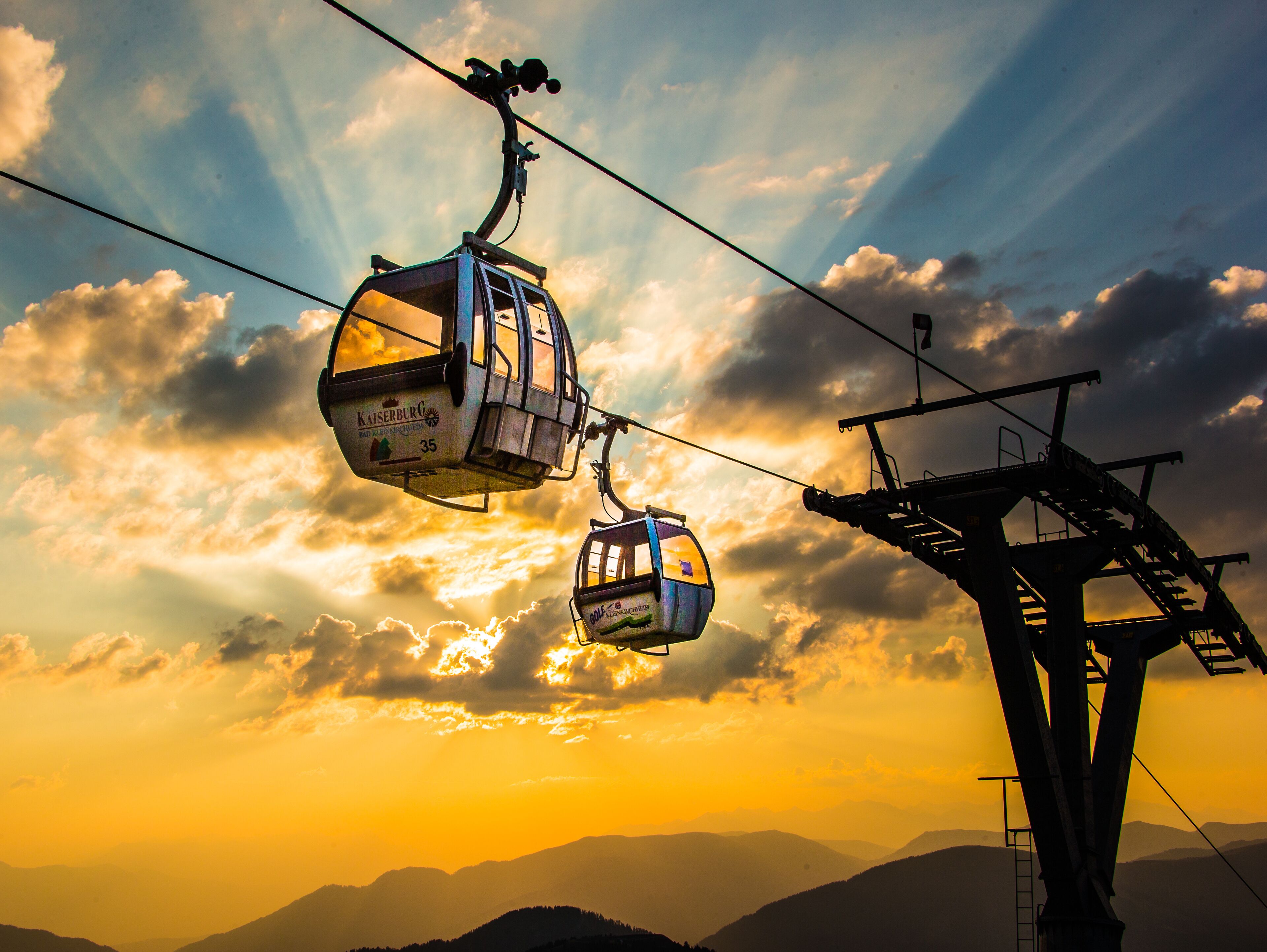 Dos teleféricos suspendidos por cables al atardecer.