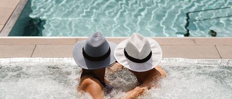 Two people in a hot tub with a view of a pool.
