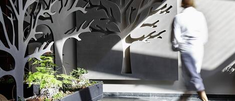 A modern indoor space with a central tree-like structure, a brick pathway, and a person walking.