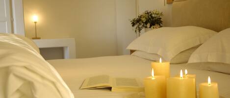 Una cama bien hecha con un libro abierto y cuatro velas encendidas sobre una bandeja.