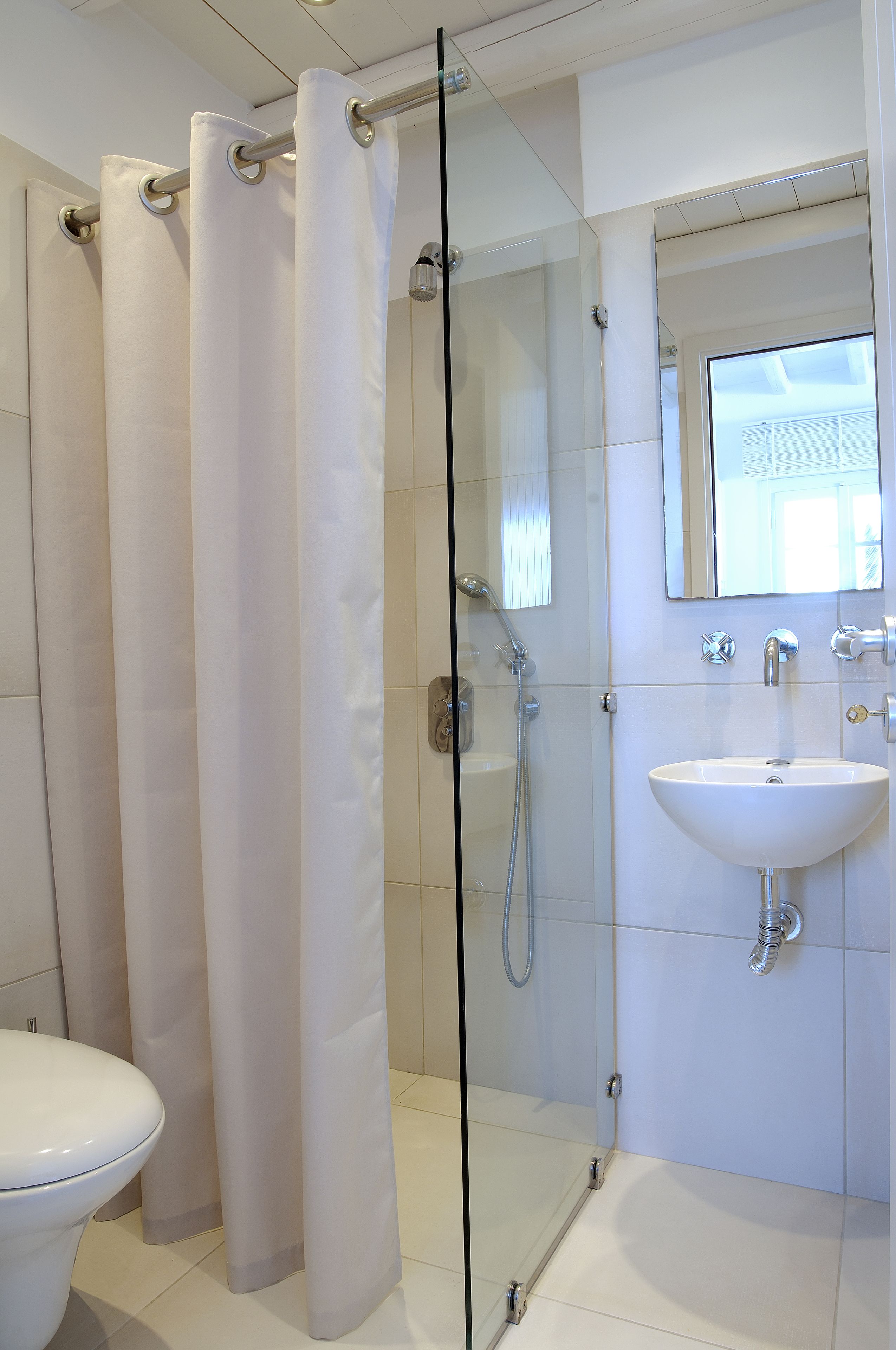 Um banheiro moderno com box de vidro, pia branca e vaso sanitário.