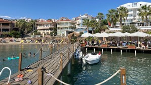 Un resort costero con un muelle de madera, sombrillas de playa y un barco atracado en el muelle.