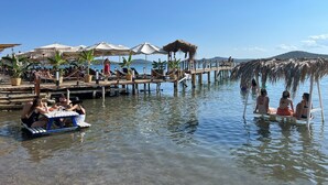 Un muelle con asientos y sombrillas de techo de paja, que se extiende sobre aguas tranquilas.