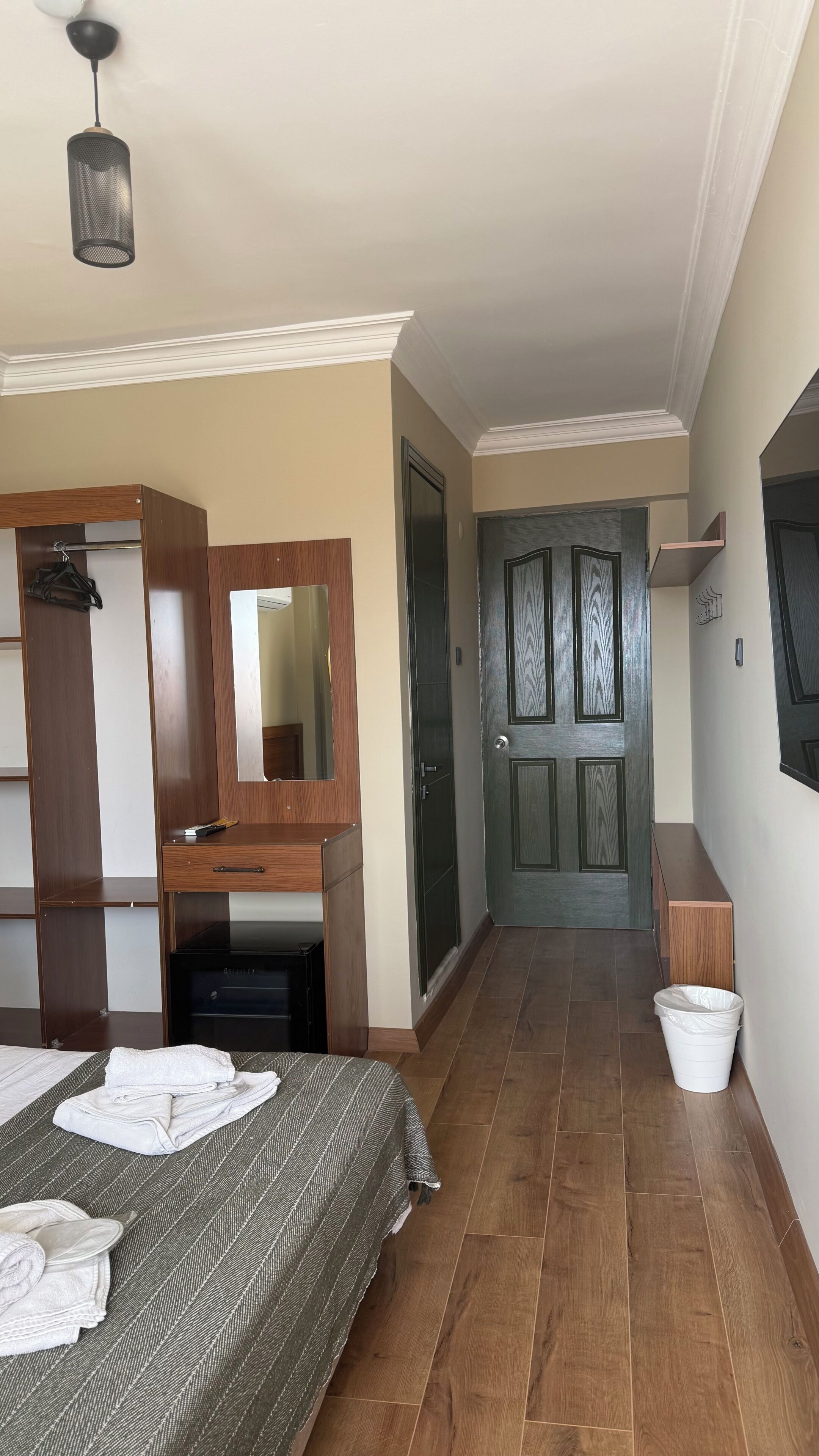 A bedroom with a bed, a dresser, a mirror, a desk, and a door.