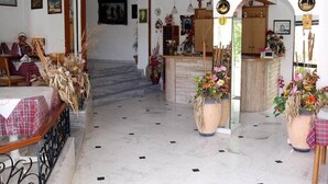 Un hall d’hôtel doté d’un sol en marbre, d’un comptoir d’accueil en bois et de divers éléments décoratifs, notamment des plantes en pot et des œuvres d’art mural.