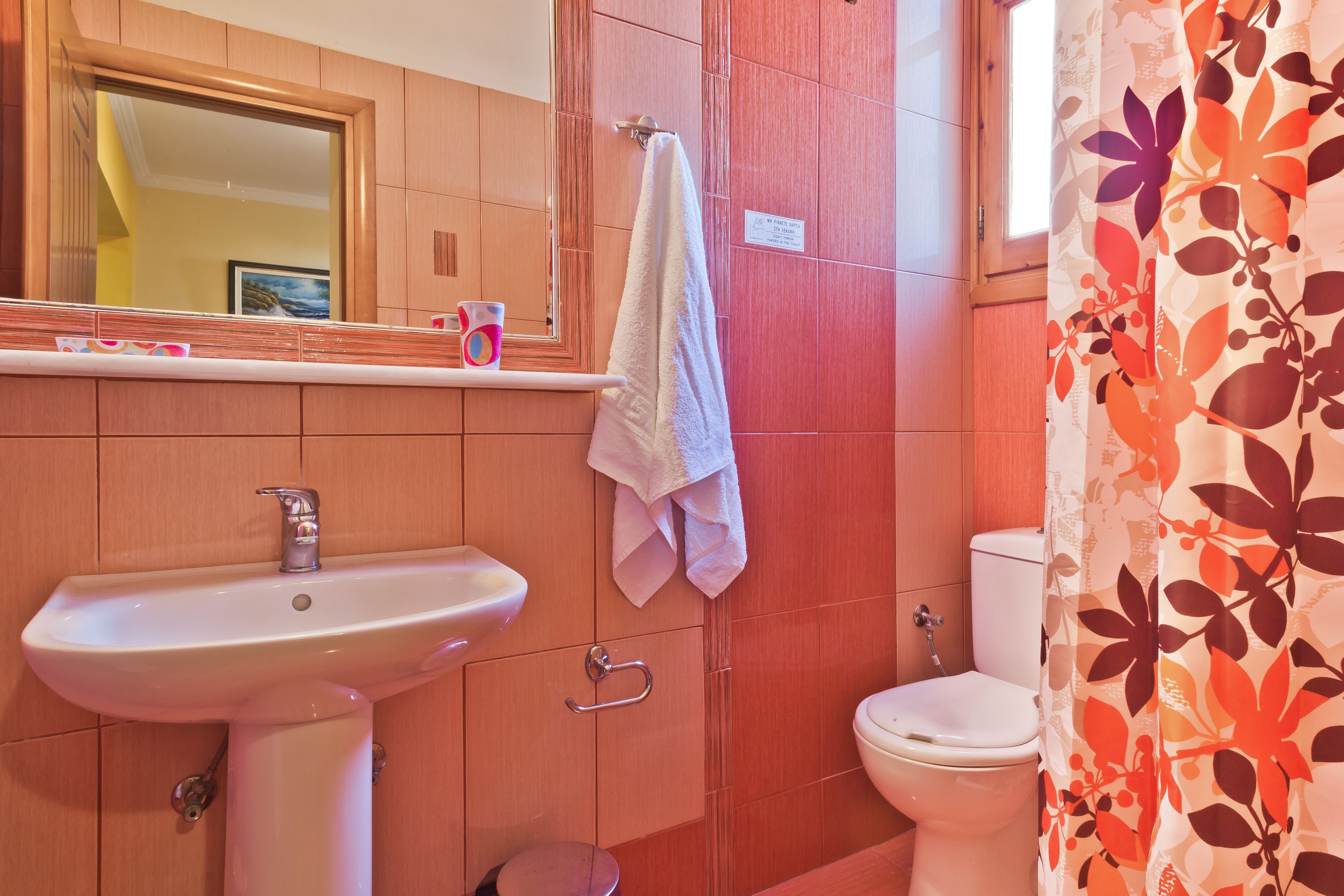 Un baño con lavamanos, espejo, inodoro y cortina de ducha.