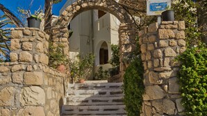 A stone staircase leading to a building entrance, surrounded by greenery and a clear blue sky. - Montemar Studios & Apartments (Karpathos)