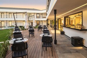 An outdoor dining area with tables and chairs, a pool, and a bar area with a counter and seating. - Mola Cunda Hotel (Ayvalik)