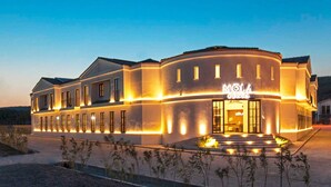 A modern hotel with a curved facade, large windows, and a well-lit entrance. - Mola Cunda Hotel (Ayvalik)