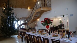 Un comedor con una larga mesa dispuesta para una comida, un árbol de Navidad y una escalera.