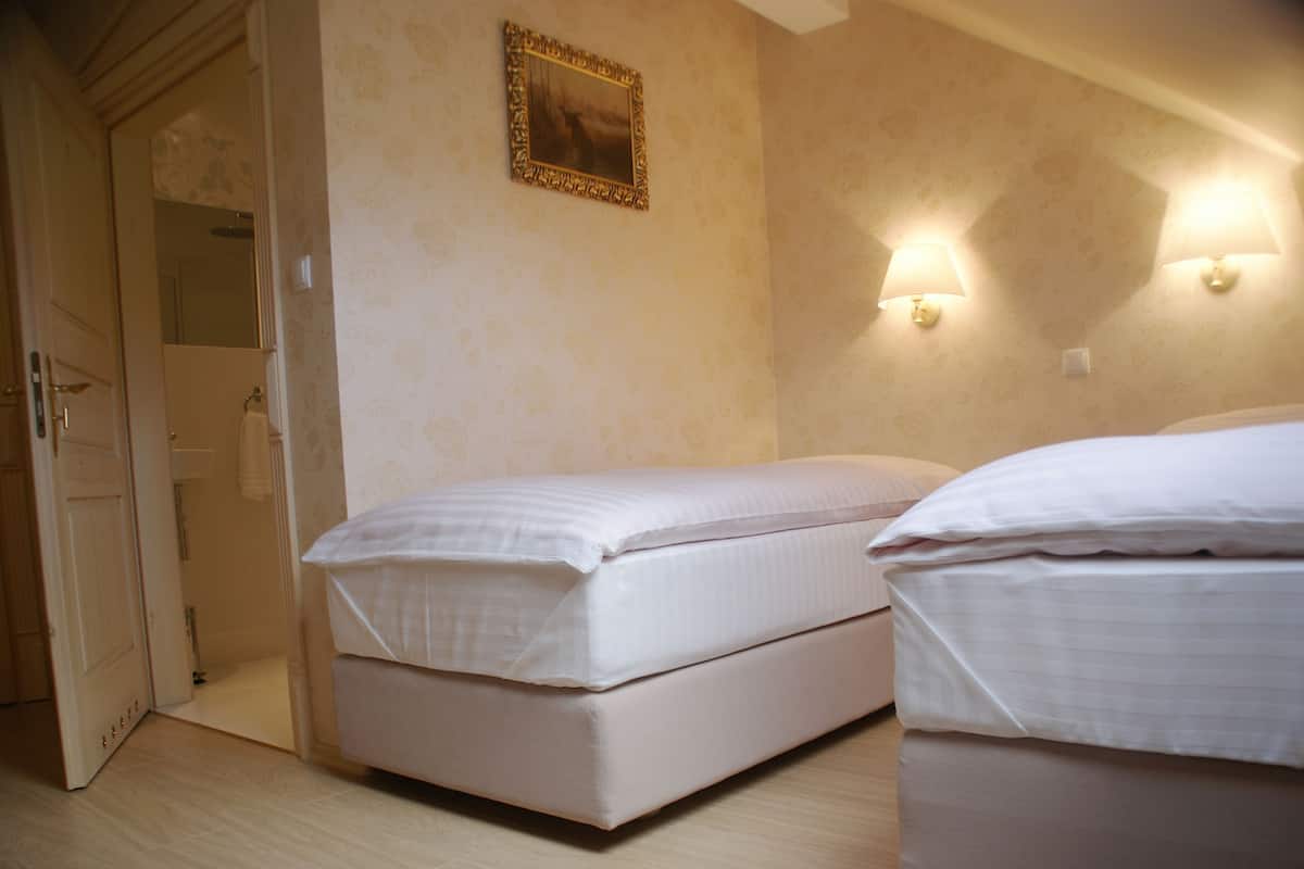 Un dormitorio con dos camas, una puerta y dos lámparas de pared.