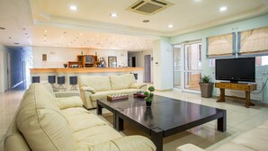 Un salon spacieux avec un canapé beige, une table basse et un téléviseur à écran plat.