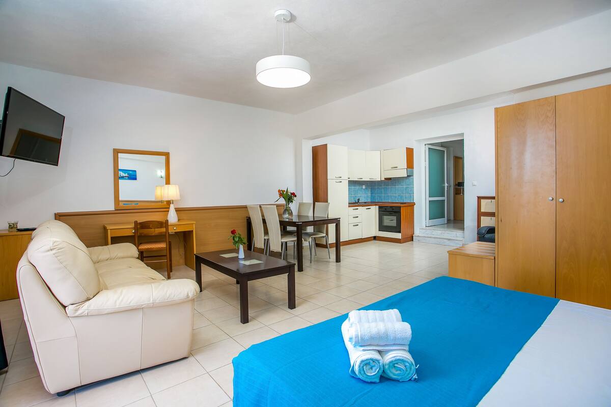 Una habitación de hotel con cama, sofá, escritorio y kitchenette.