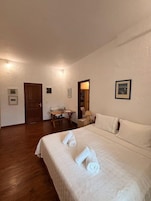 Una habitación de hotel con una cama grande, un escritorio de madera, una silla y una mesita.