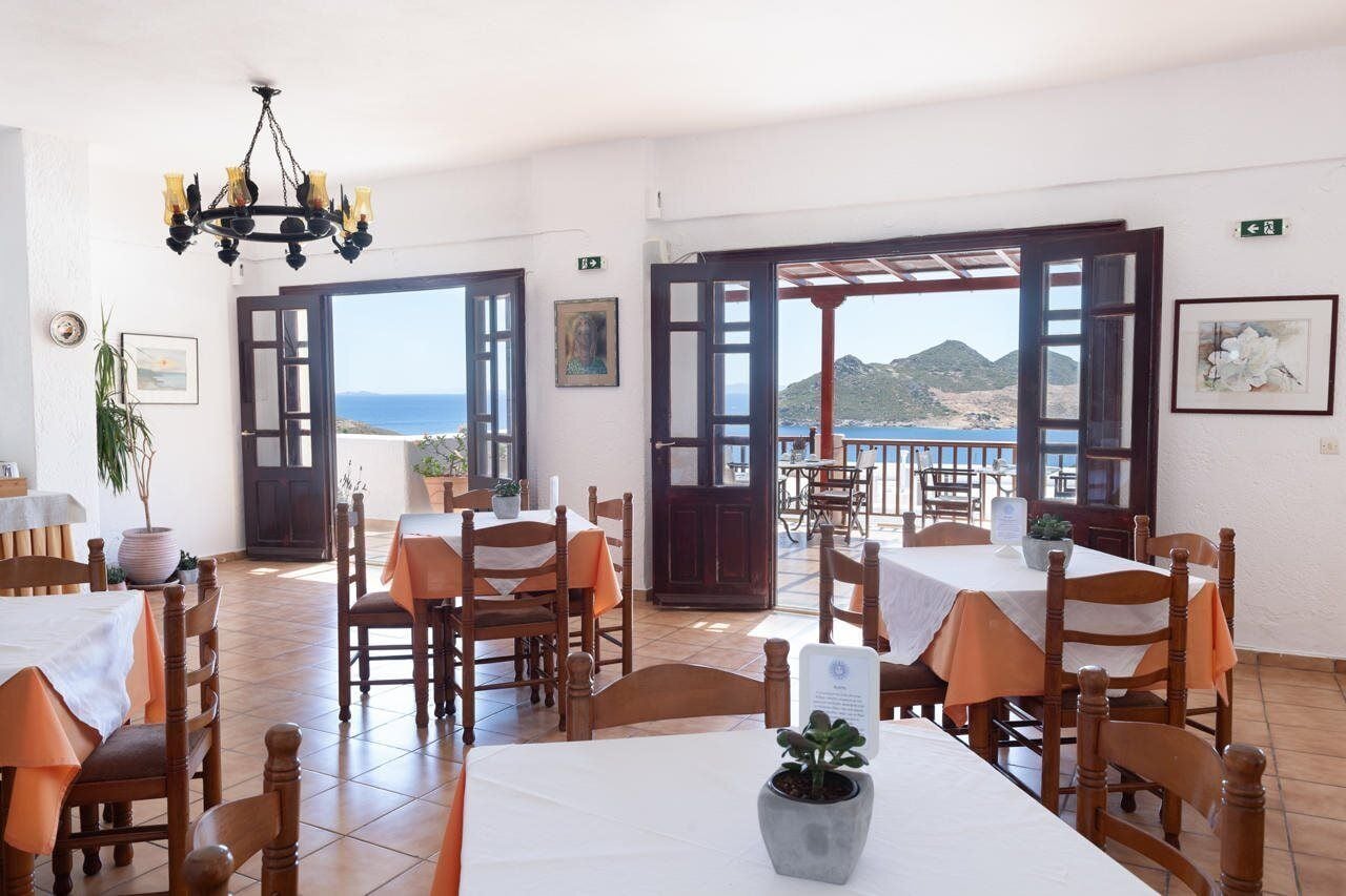 A dining area with tables and chairs, a chandelier, and a view of the sea.