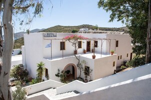 Un edificio blanco con un letrero que dice 'HOTEL Golden Sun'. Cuenta con un balcón con plantas en macetas y vistas a una colina.