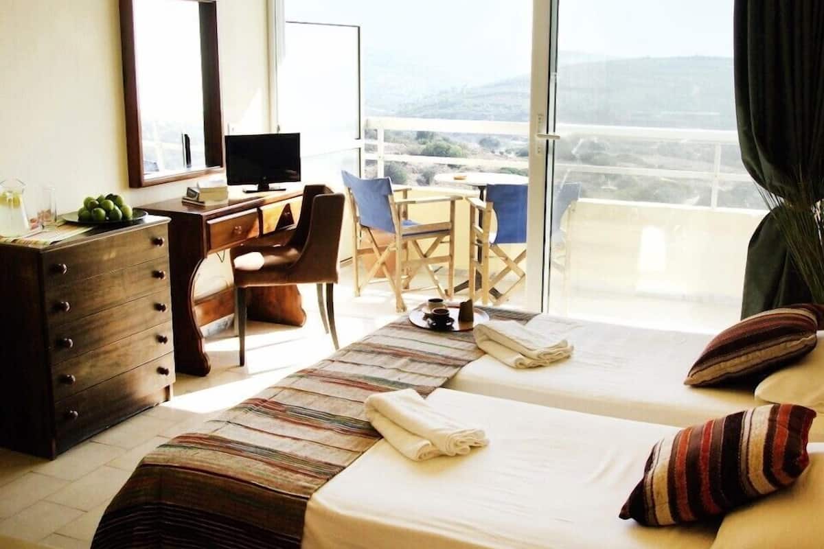Une chambre d’hôtel avec deux lits, un bureau, une chaise, une télévision et une vue sur la ville.
