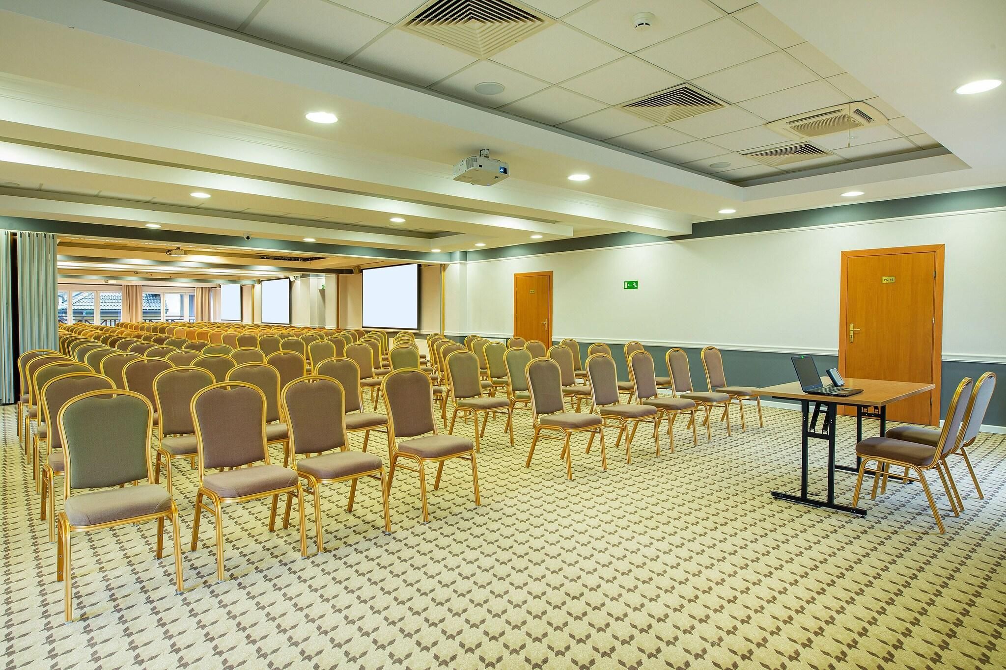 A conference room with rows of chairs, a projector, and a laptop on a table.