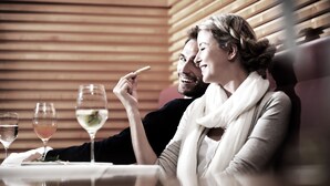 A couple dining at a table with wine glasses, in a room with wooden paneling. - Reduce Hotel Vital (Bad Tatzmannsdorf)