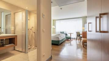 Una camera d'albergo con doccia, letto, scrivania e sedia.