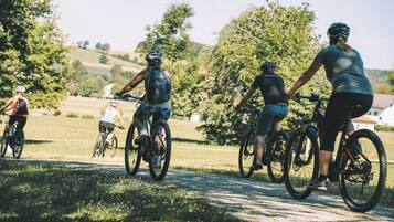 A group of cyclists on a paved path surrounded by greenery.