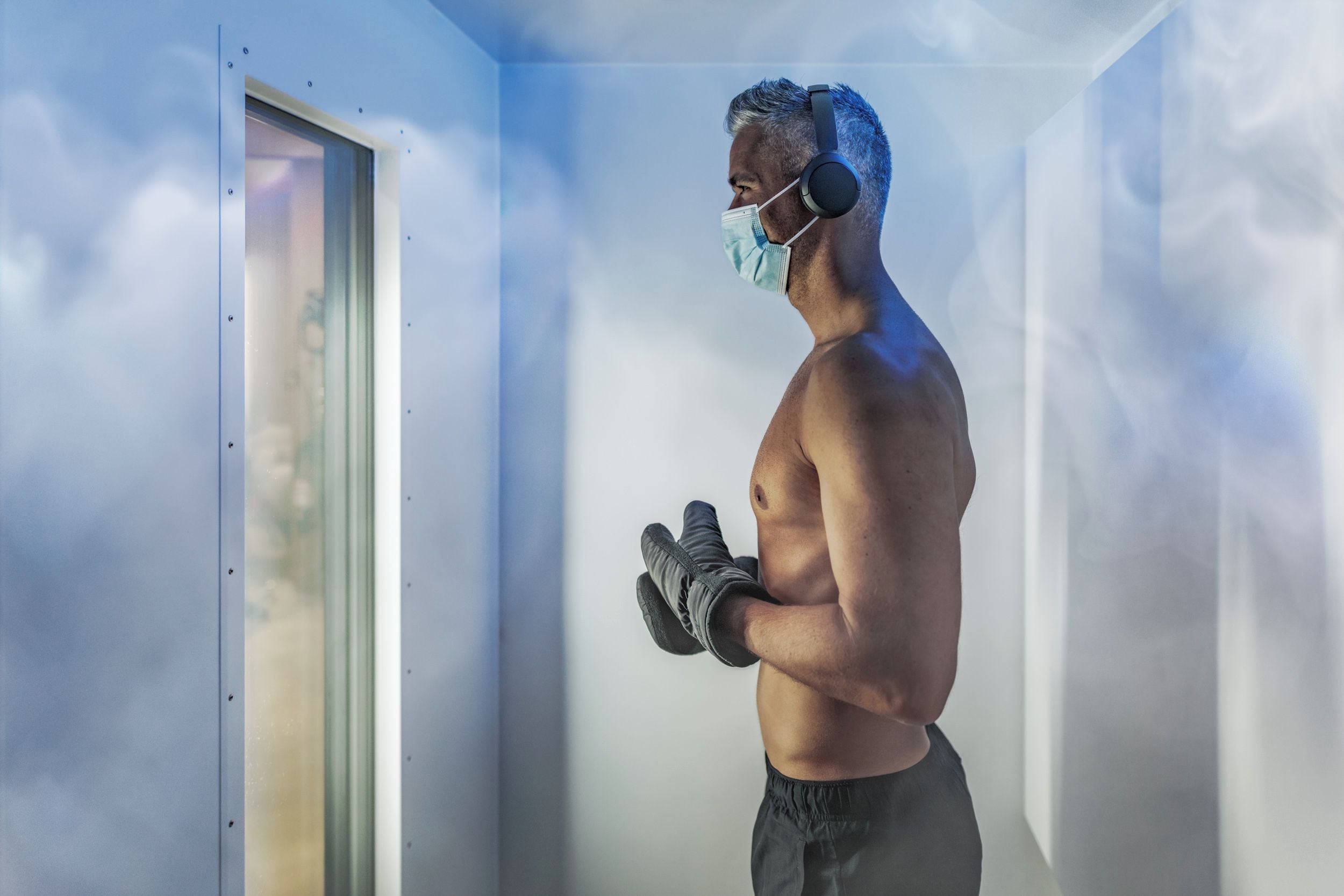 Una persona de pie en una habitación con una ventana, usando guantes y una mascarilla.