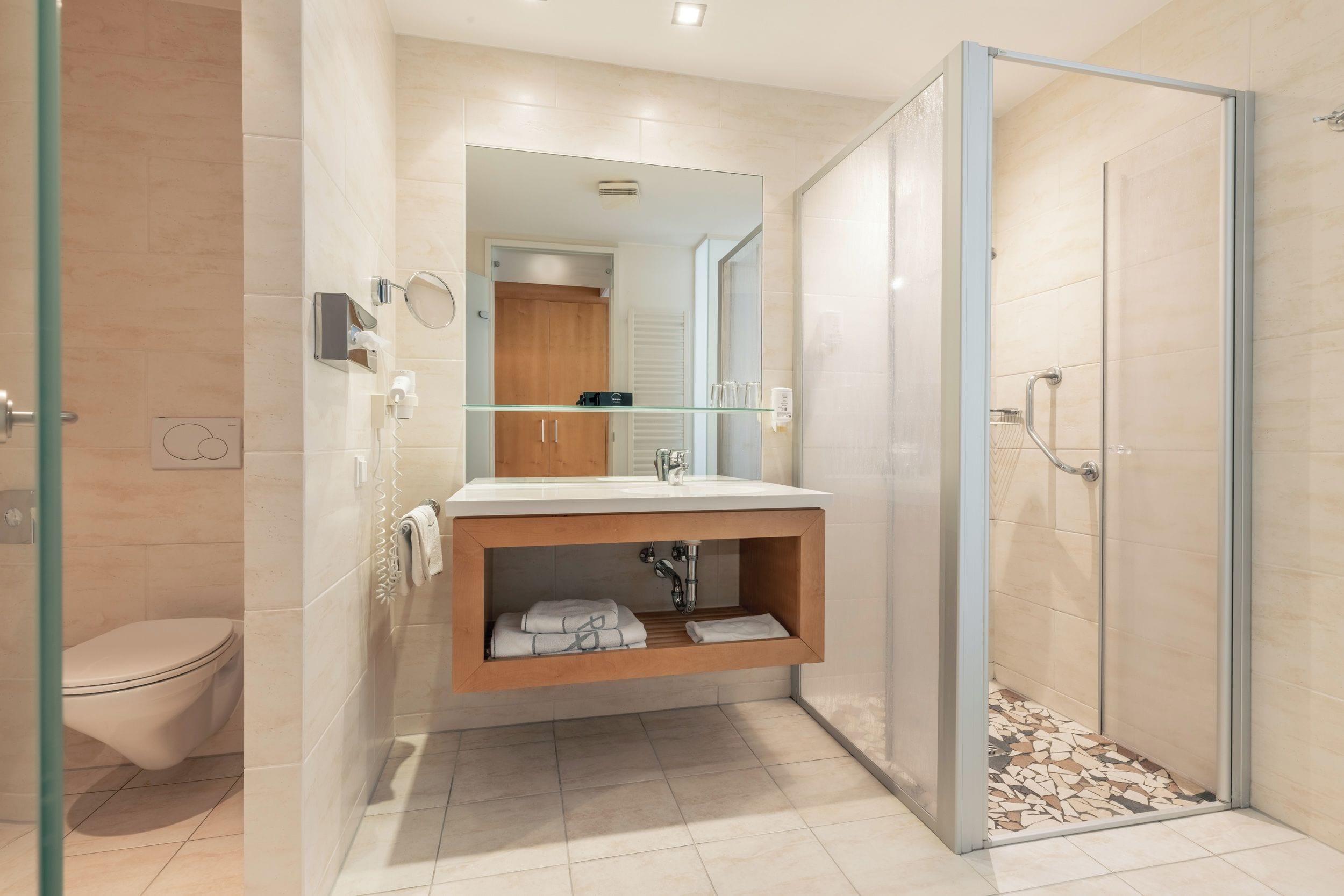 Un baño moderno con cabina de ducha de vidrio, un lavamanos empotrado con espejo y un inodoro.