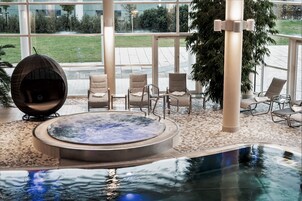 Una piscina techada, una piscina al aire libre, sombrillas