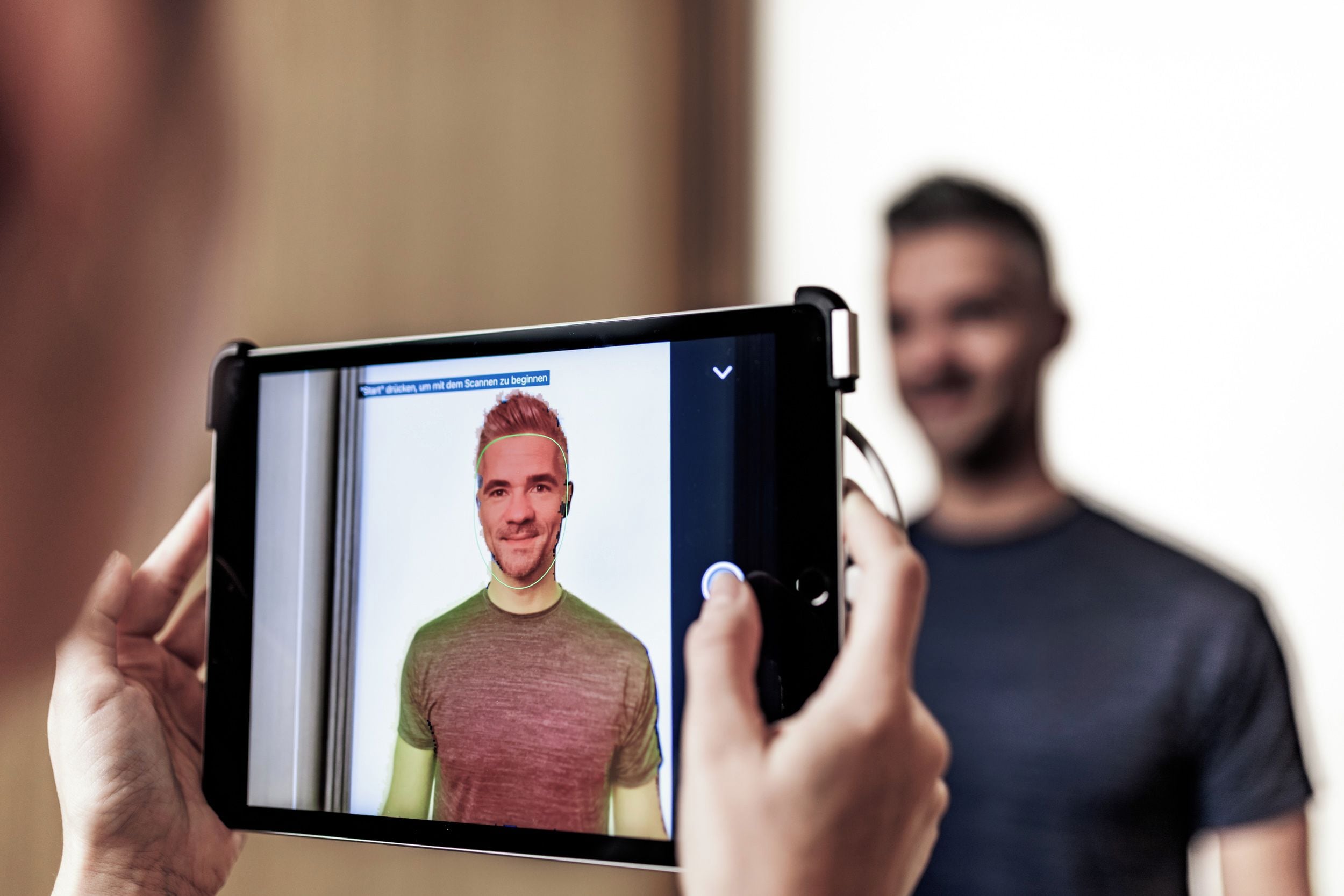 A person holding a tablet displaying a photo of another individual.
