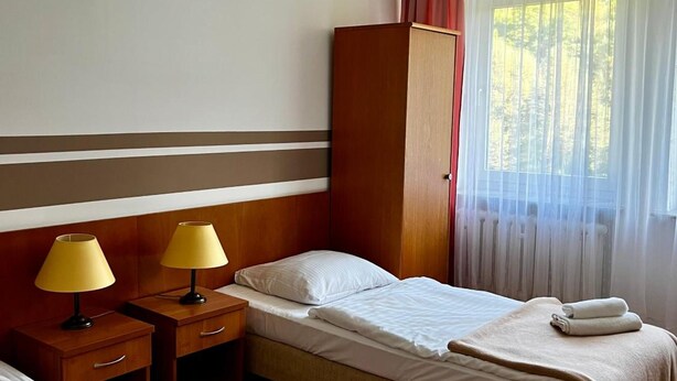 A hotel room with two beds, a wardrobe, a desk with lamps, and a window with curtains. - Geovita Centrum Konferencyjno - Rekreacyjne (Ladek-Zdrój)