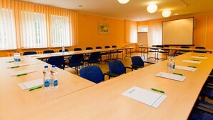 A conference room with long tables, chairs, water bottles, name tags, and a projector screen. - Geovita Centrum Konferencyjno - Rekreacyjne (Ladek-Zdrój)