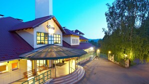 A hotel with a covered outdoor seating area, a staircase leading to the entrance, and a pathway flanked by trees. - Geovita Centrum Konferencyjno - Rekreacyjne (Ladek-Zdrój)