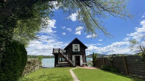A wooden cabin with a balcony, a small deck, and a view of a lake. - Dietrichsteinerhof Apartments & Rooms (Finkenstein am Faaker See)