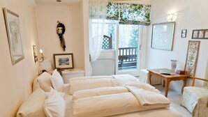 A bedroom with a large bed, a wooden nightstand, a small table, and a balcony with a view. - Dietrichsteinerhof Apartments & Rooms (Finkenstein am Faaker See)
