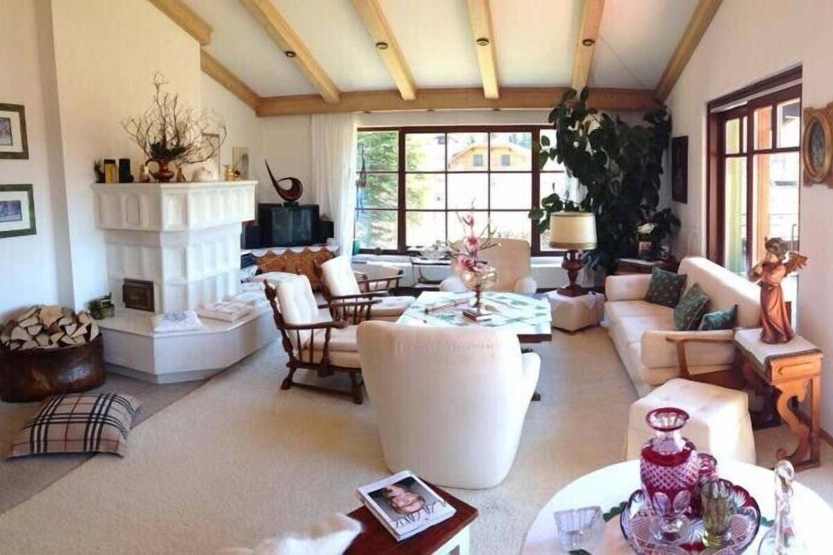 A spacious living room with a fireplace, comfortable seating, and large windows offering a view of the outdoors.